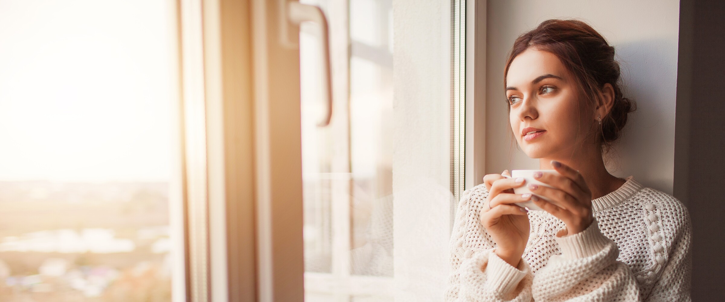 Solemn woman drinking tea by the window